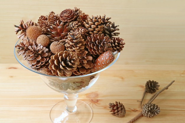 Composición con varios tipos de piñas secas en un vaso.