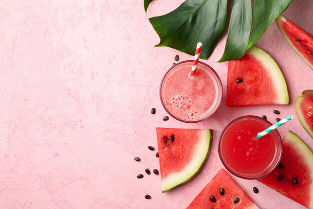 Foto composición con vaso de jugo de sandía y rodajas en mesa rosa