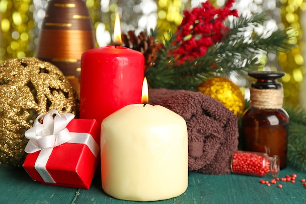 Composición de velas encendidas, toalla y aceite aromático en la mesa de madera verde