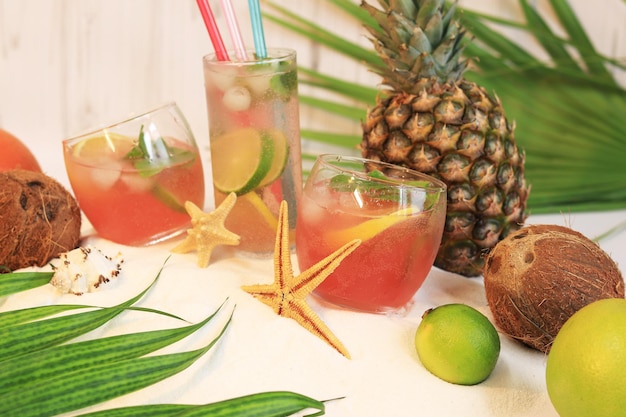 Composición de verano con copas de cóctel con limonada o alcohol en la playa