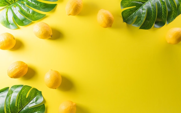 Composición de verano hecha de limón o lima y hoja de monstera sobre fondo amarillo pastel Concepto mínimo de fruta Espacio de copia de vista superior plana