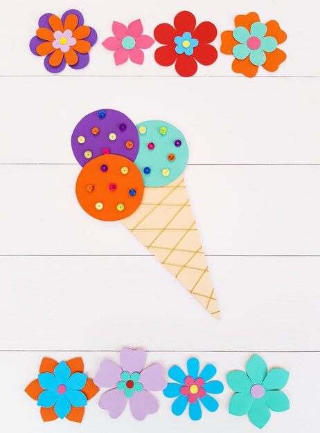 Composición vertical de flores de verano, cuerno de helado de papel multicolor y lentejuelas. El niño hace manualidades con sus propias manos. Bonita creatividad artística hecha a mano en una mesa de madera. Vista superior, espacio de copia