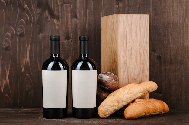 Composición del vino con pan, dos botellas en caja y copa de vino en la mesa de madera