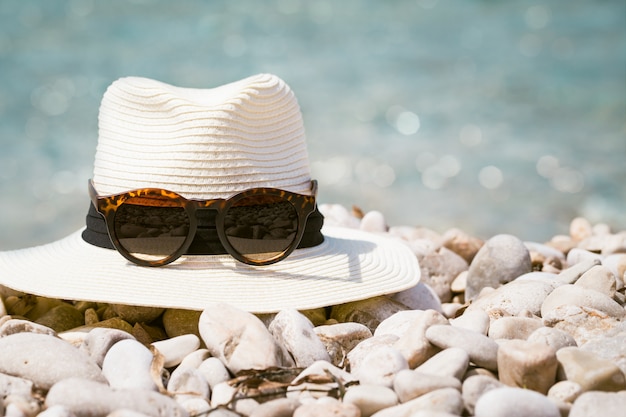 Composiciones de verano con sombrero de mujer y gafas de sol en la playa.