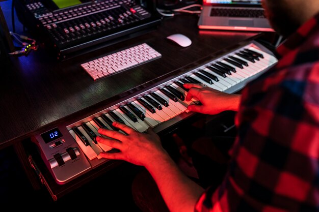 El compositor de hombre está tocando el teclado en el estudio de grabación para radio fm