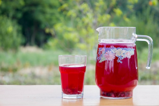 Compota vermelha de frutas em um copo e jarra