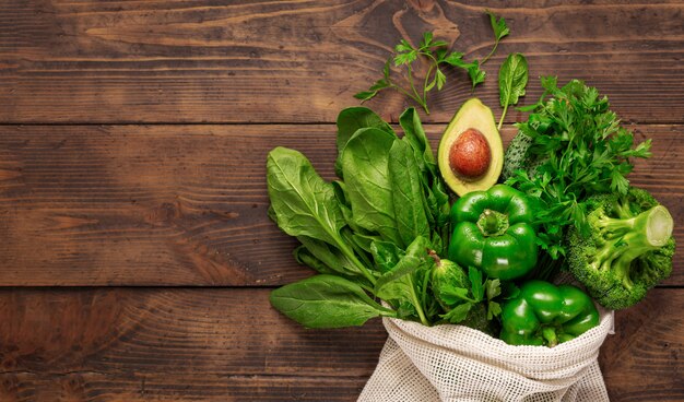 Compra comida saludable. Vista superior de la bolsa de compras con alimentos sanos comer limpio. Verdura verde en la vista superior de fondo de madera