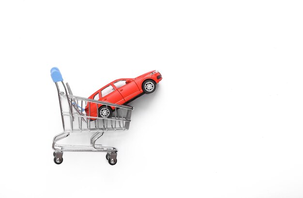 Compra de un concepto de coche Carrito de compras con modelo de coche de juguete en fondo blanco