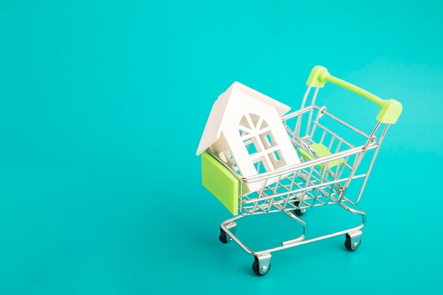 Compra de habitação a crédito uma casa em um carrinho de compras em um fundo verde com espaço de cópia