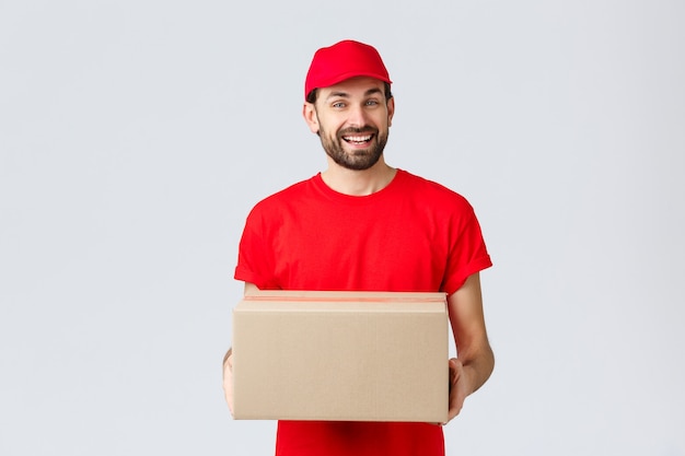 Compra online de entrega de pedidos e conceito de envio de pacotes. Correio amigável e sorridente em uniforme vermelho ...