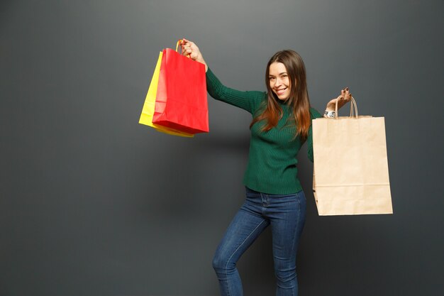 Foto compra y venta. viernes negro. mujer feliz tiene bolsa de color junto a la pared negra.