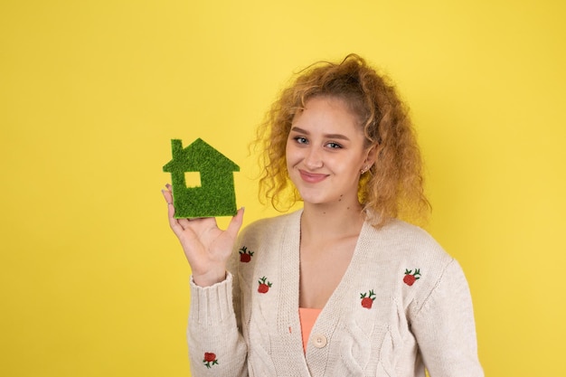 Comprador de casa feliz Una niña sostiene un modelo de una casa verde en sus manos El concepto de ecología de energía verde