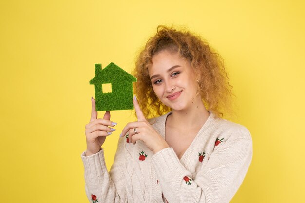 Comprador de casa feliz Una niña sostiene un modelo de una casa verde en sus manos El concepto de ecología de energía verde