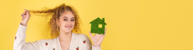 Comprador de casa feliz Una niña sostiene un modelo de una casa verde en sus manos El concepto de ecología de energía verde