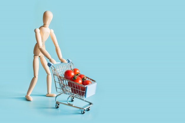 Comprador como muñecos de madera con carrito de supermercado y tomates.