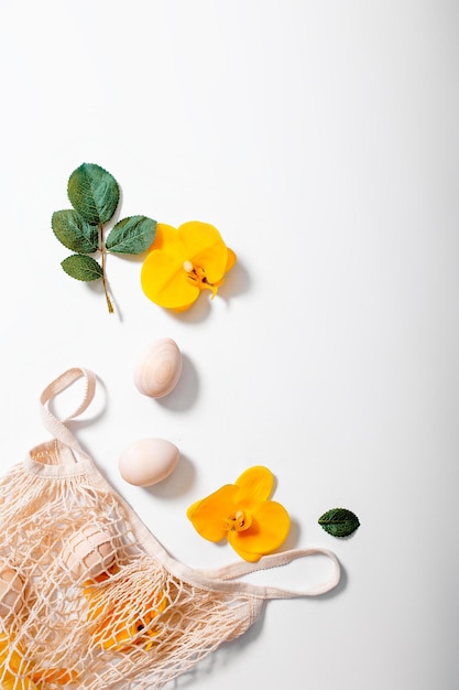 Foto comprador de malha com ovos e flores em fundo branco cartão de feliz páscoa com flores e folhas verdes