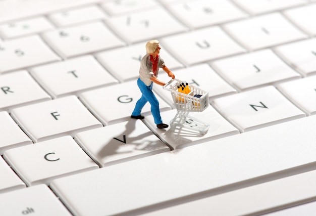 Comprador empurrando um carrinho sobre um teclado de computador