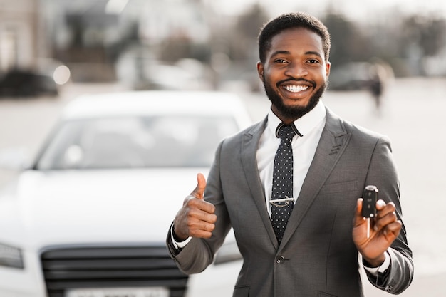 Comprador feliz con llaves cerca de coche nuevo