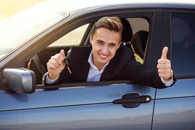 Comprador feliz sosteniendo las llaves del auto dentro de su nuevo vehículo