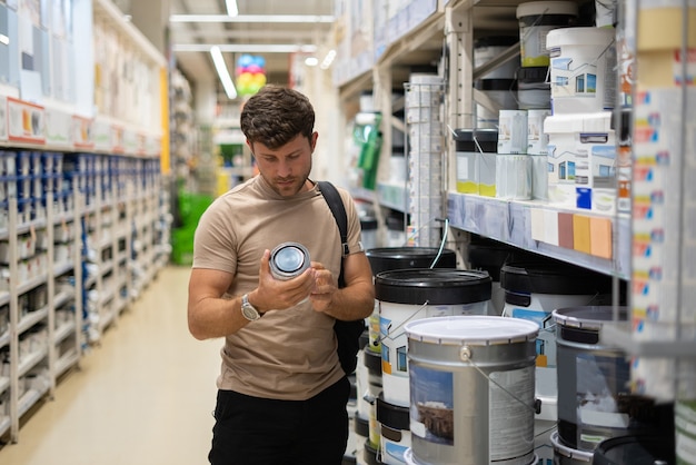 Comprador lendo etiqueta na lata de tinta