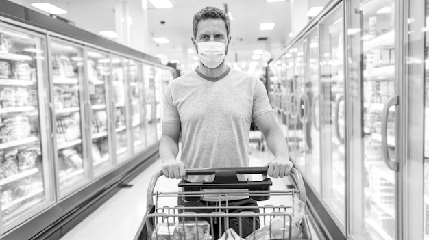 Comprador con máscara de protección con carrito de compras comprando comida en el supermercado