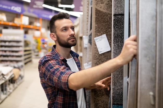 Comprador masculino en una ferretería elige suelo de moqueta