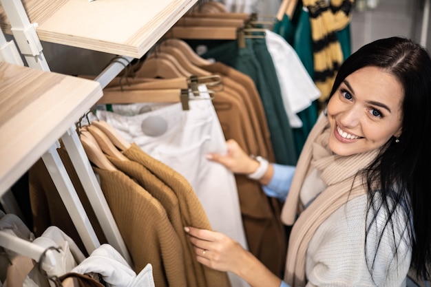 Foto comprador de mujer feliz relajante disfrutando de venta porcentual en boutique de moda eligiendo ropa