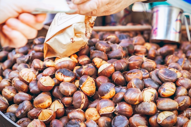 Comprador paga por castanhas grelhadas a carvão no mercado de alimentos de outono