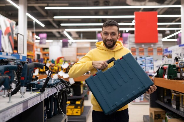 Comprador satisfecho de una tienda de herramientas eléctricas sosteniendo un caso con una sonrisa