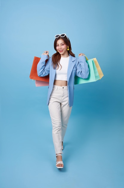 compradora asiática caminhando e segurando uma bolsa de compras sentindo-se feliz entusiasmada com o desconto
