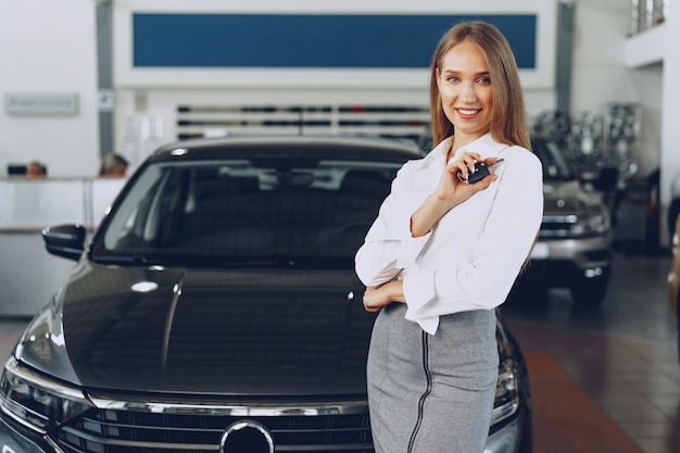 Compradora / vendedora jovem feliz perto do carro com as chaves na mão