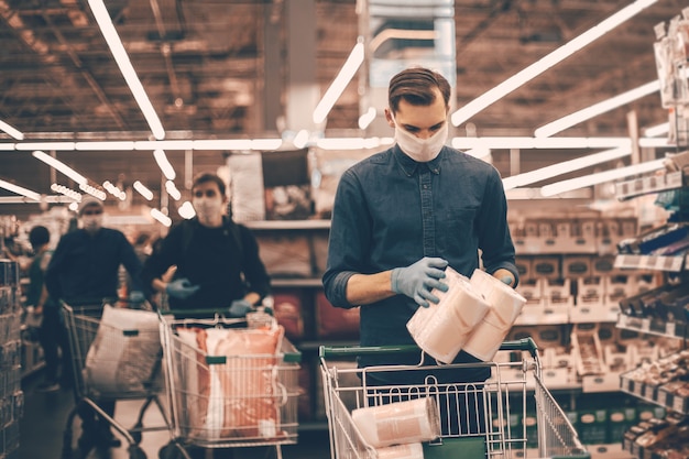 Compradores con carritos de compras eligiendo productos en el supermercado.