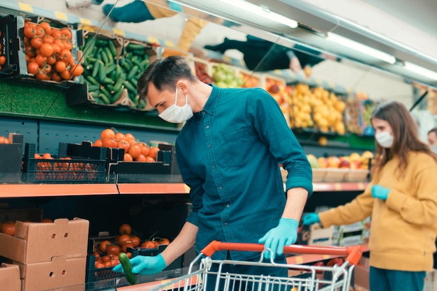 Compradores com máscaras protetoras escolhendo frutas no supermercado. coronavírus na cidade