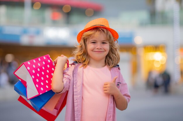 Comprando crianças na loja de moda criança da moda com sacola de compras ao ar livre pequena compradora