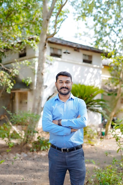 Comprando o conceito de casa Homem indiano segurando uma nota indiana em uma mão e parado na frente da casa