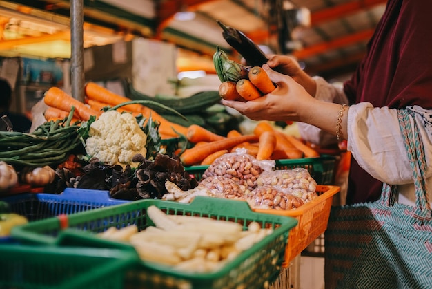 Comprando produtos orgânicos frescos no mercado dos fazendeiros. A mão da mulher escolhe vários legumes frescos.