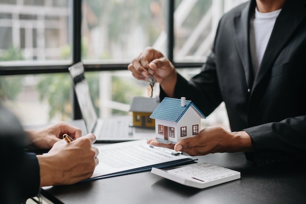 Comprar una casa o un contrato de seguro Un agente de seguros apuntando con un bolígrafo a los interesados en alquilar una casa Un contrato Firmando un acuerdo de compra de vivienda