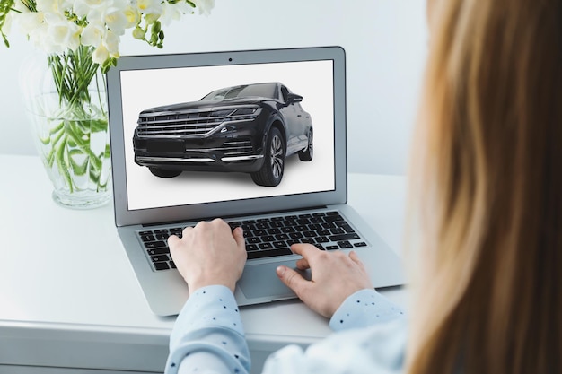 Foto comprar en línea mujer eligiendo coche usando la vista de cerca de la computadora portátil