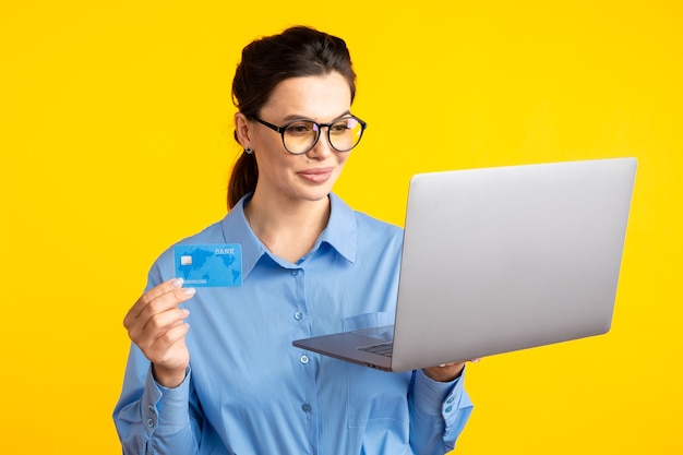 Comprar en linea. Mujer sosteniendo portátil y eligiendo cosas para comprar en amarillo