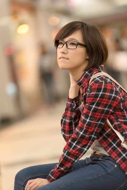 Compras chica joven de Asia sentarse en un banco en el centro comercial en Taipei, Taiwán.