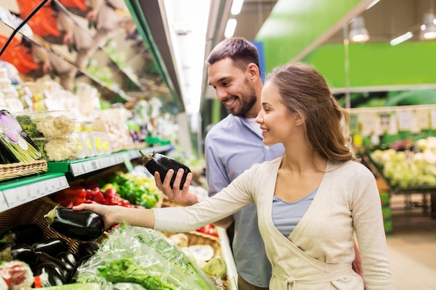 compras, comida, venda, consumismo e conceito de pessoas - casal feliz comprando abacate na mercearia ou no supermercado