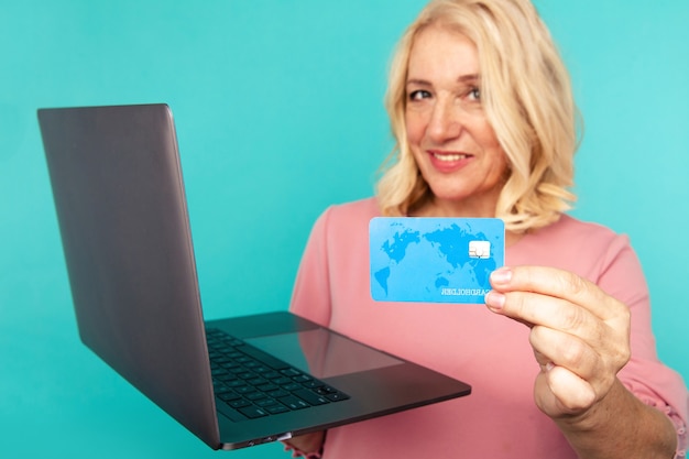 Compras en la computadora. Mujer sonriente con laptop y tarjeta de crédito haciendo compras en línea.