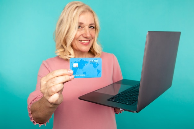 Compras en la computadora. Mujer sonriente con laptop y tarjeta de crédito haciendo compras en línea.