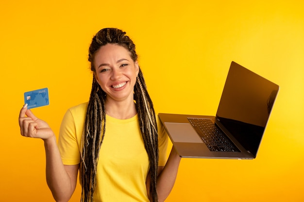 Compras en la computadora. Mujer sonriente con laptop y tarjeta de crédito haciendo compras en línea.
