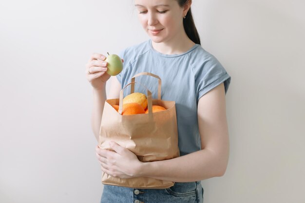 Compras de alimentação saudável e conceito ecológico próximo de uma mulher segurando uma sacola ecológica com frutas em fundo branco