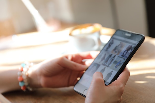 Compras de mão de mulher com telefone na cafeteria