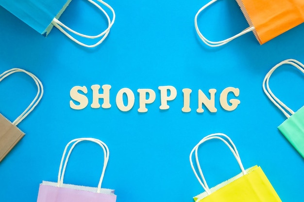 Compras de palavras de madeira e sacos de papel em uma vista superior de fundo azul