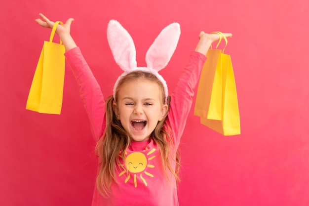 Foto compras de páscoa emoção emocionada surpresa criança adorável menina em orelhas de coelho traje de coelho segurar