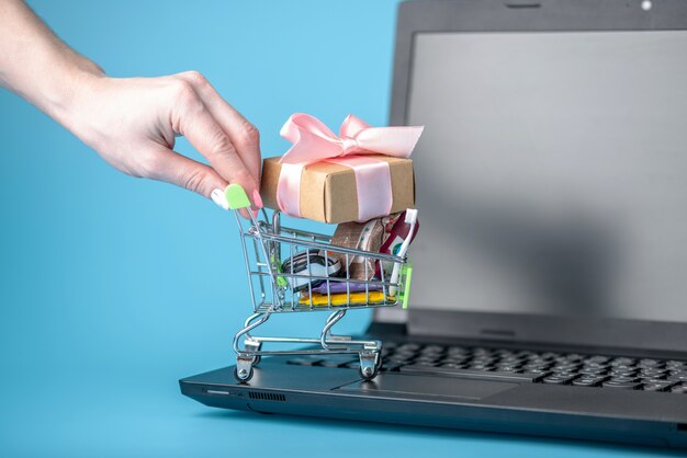 Compras diarias en el carrito de compras en el teclado del portátil sobre un fondo azul.