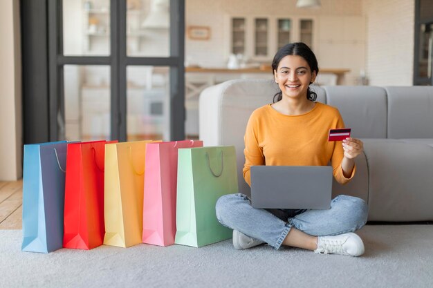 Compras por Internet Mujer india usando portátil y tarjeta de crédito para compras en línea